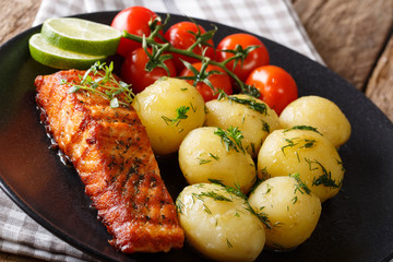 Roasted fillet of salmon with thyme and boiled potatoes, fresh tomatoes close-up. horizontal