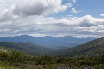 Summer in the mountains. Mountain ranges over the forest. Panoramic view of the mountains.