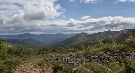 Summer in the mountains. Mountain ranges over the forest. Panoramic view of the mountains.