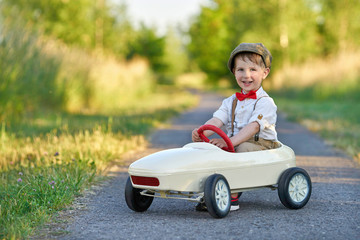 fröhlicher Junge im nostalgischen Tretauto