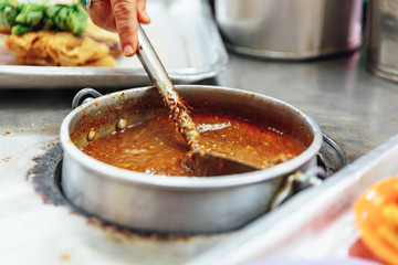 Warming satay sauce in the pot. Satay is a dish of skewered grilled meat with Javanese origins in Malacca City, Malacca, Malaysia.