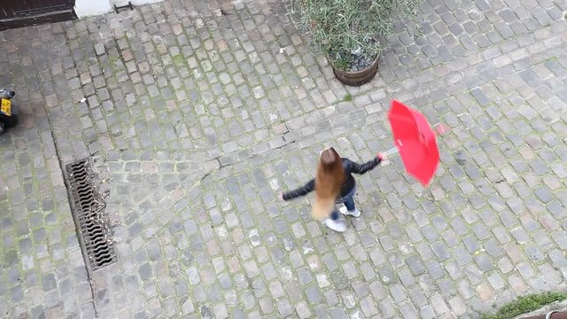 top view of girl turning around with red umbrella on the street and looking to camera, carefree and happiness 