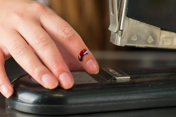Close up of a youn woman injured her finger using a stapler, bleeding