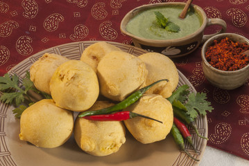 Batata Vada with garlic and mint chutney and chilli on white plate  