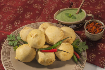 Batata Vada with garlic and mint chutney and chilli on white plate  