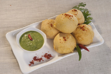 Batata Vada with garlic and mint chutney and chilli on white plate  