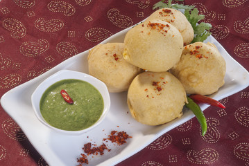 Batata Vada with garlic and mint chutney and chilli on white plate  