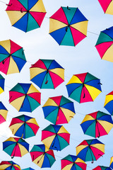 Colorful umbrellas background. Coloruful umbrellas urban street decoration. Hanging Multicoloured umbrellas over blue sky