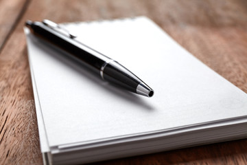 Pen on notepad on the wooden table. writing and thinking concept.