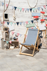 Outdoor photo zone with sea theme decoration. Summer vacation street photozone, flags, seagulls and lounger waiting for tourist to rest or make a selfie photo.