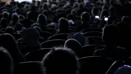 The audience applauded for a performance or presentation in the theater. Video from the back. Children and adults alike