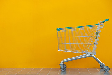 Empty shopping cart parking on yellow background with copyspace. retail store.