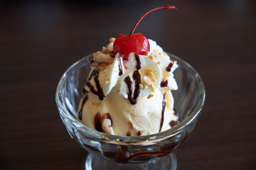 Ice cream chocolate and vanilla sundae topping with red cherry.