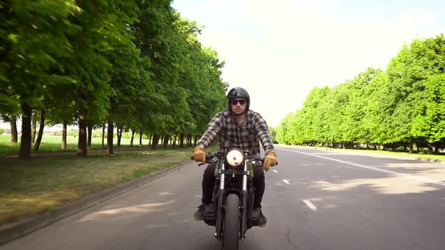 Biker riding a motorcycle on a road surrounded by trees