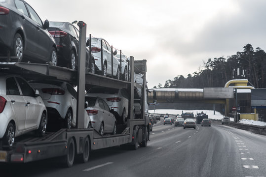 The trailer transports cars on highway.