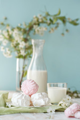 Good morning! Russian marshmallow with bottle and glass of milk on wooden background. Spring composition. Sweet breakfast in pastel colors on green napkin. Healthy food. Rustic style.