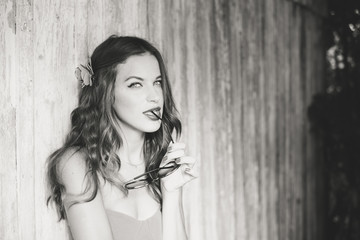 Young sexy stylish lady in front of wooden door on sunny summer day. Lifestyle black and white portrait outdoor background