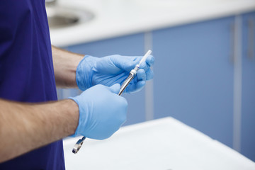 Hand of dentist holding dental syringe