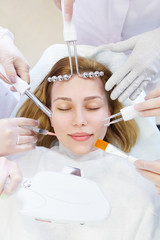 Naklejka premium Beauty treatment and cosmetology concept. Hands of several beauticians holding their respective equipment near patient face