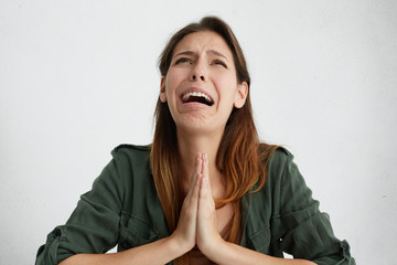 Portrait of desperate woman begging for mercy and crying. Emotional woman holding her palms...