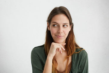 Headshot of cunning beautiful woman with straight dyed hair looking aside holding hand under chin...