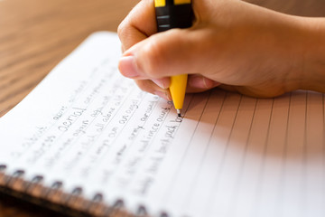 Child writing by hand on notepad