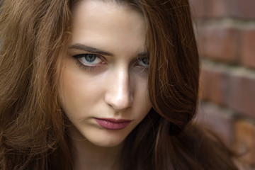 Naklejka premium Girl with long hair near an old brick wall