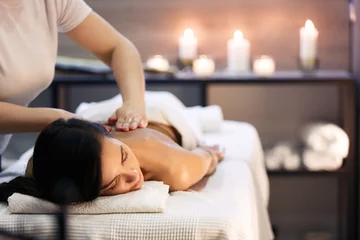 Wall murals Spa Body massage and spa treatment in modern salon with candles