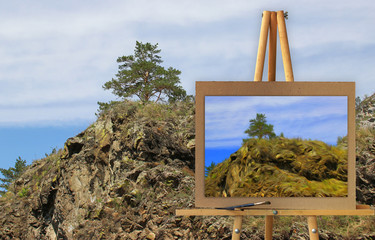 Easel with a painting watercolor illustration of Altai Mountains on a canvas on a landscape.   Photo manipulation concept.