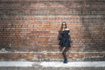 Girl with long hair near an old brick wall