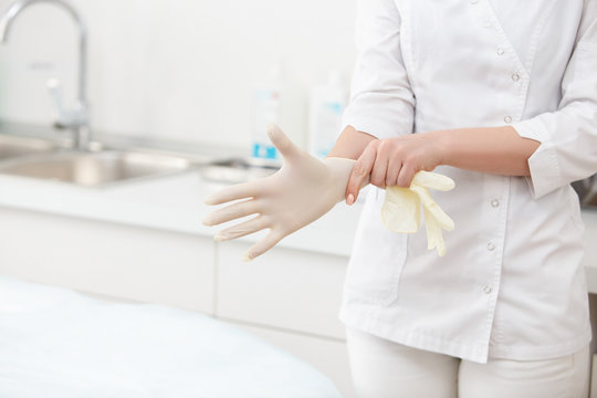 Blue latex medical gloves on a female hand, one hand pulls on a glove