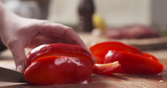 Slide slow motion shot of female teen hands slicing red bell pepper inlong pieces for grill, 4k 60fps prores footage