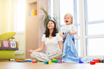 Portrait of young happy yoga mom spending time with her little baby boy