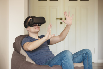 Fototapeta na wymiar Man plays game with virtual reality glasses indoors