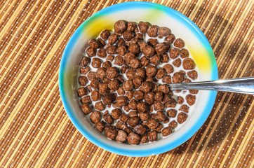 Flakes of cereals in a blue plate on a bamboo napkin