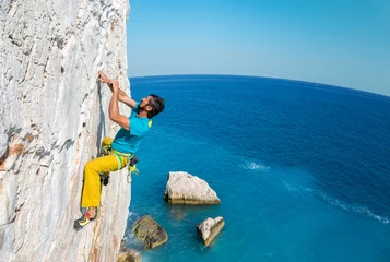 Crédence de cuisine en verre imprimé Alpinisme Adult Mountain Climber hanging on Rock over Sea