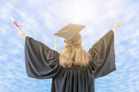 Woman graduate celebrating with certificate in her hand with blue sky background.