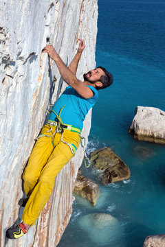 Portrait of mature Rock Climber hanging on vertical Rock Wall