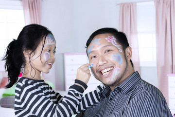 Father and daughter play together in the bedroom