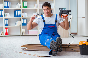 Young worker working on floor laminate tiles