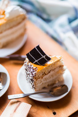 a beautiful delicious cake and the pieces in three white saucers on beige yellow cutting Board