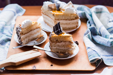 a beautiful delicious cake and the pieces in three white saucers on beige yellow cutting Board