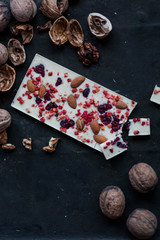 white chocolate with red berries and walnut whole nuts on black background