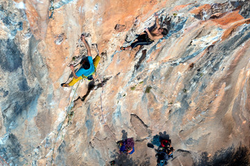 Two Rock Climbers moving up on vertical Wall high