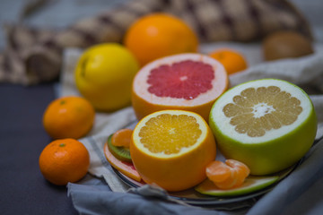 bright juicy citrus fruits in the dish and brown light beige kitchen towel in the kitchen, the festive table closeup