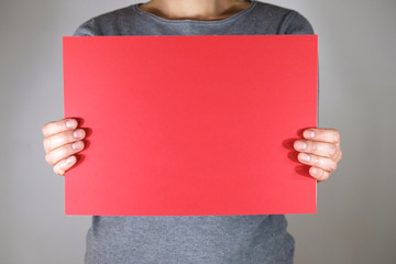 Two hands holding blank red paper sheet