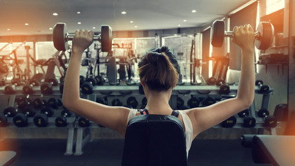 woman weight lifting dumbbell bodybuilding in workout fitness gym