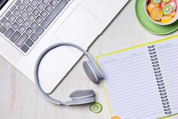 Candies, headphones and notepad on wooden table. Open space for copy.