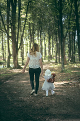 Mother and baby girl walking in the forest in the sunset light