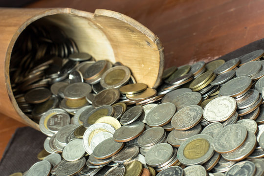 Thai baht coins collected in a bamboo flask, are from the change from variety of sources. The coins in variety of amount, are poured out to exchange for banknotes or deposit into the bank account.